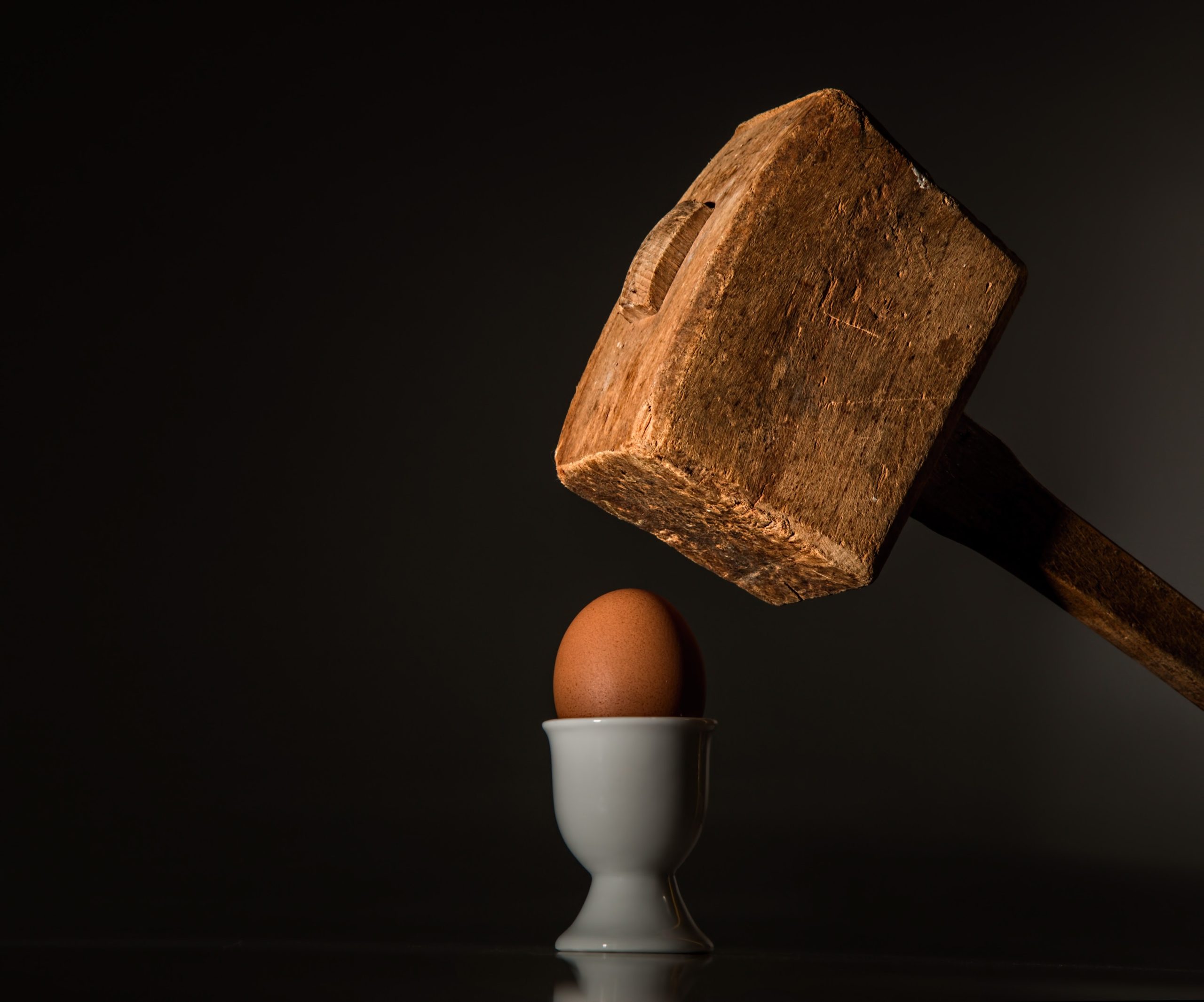 Ein Hammer schlägt auf ein Ei